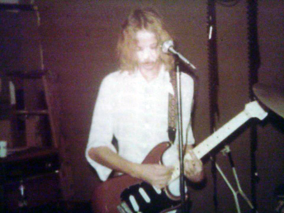Faron Collins with long hair playing a chocolate Stratocaster
